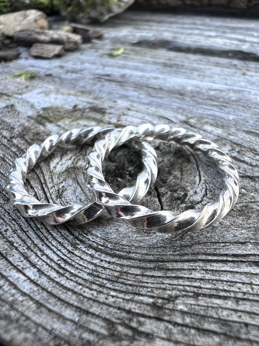Recycled sterling silver thin square twist rings on weathered wood, showing the twisted wire band detail