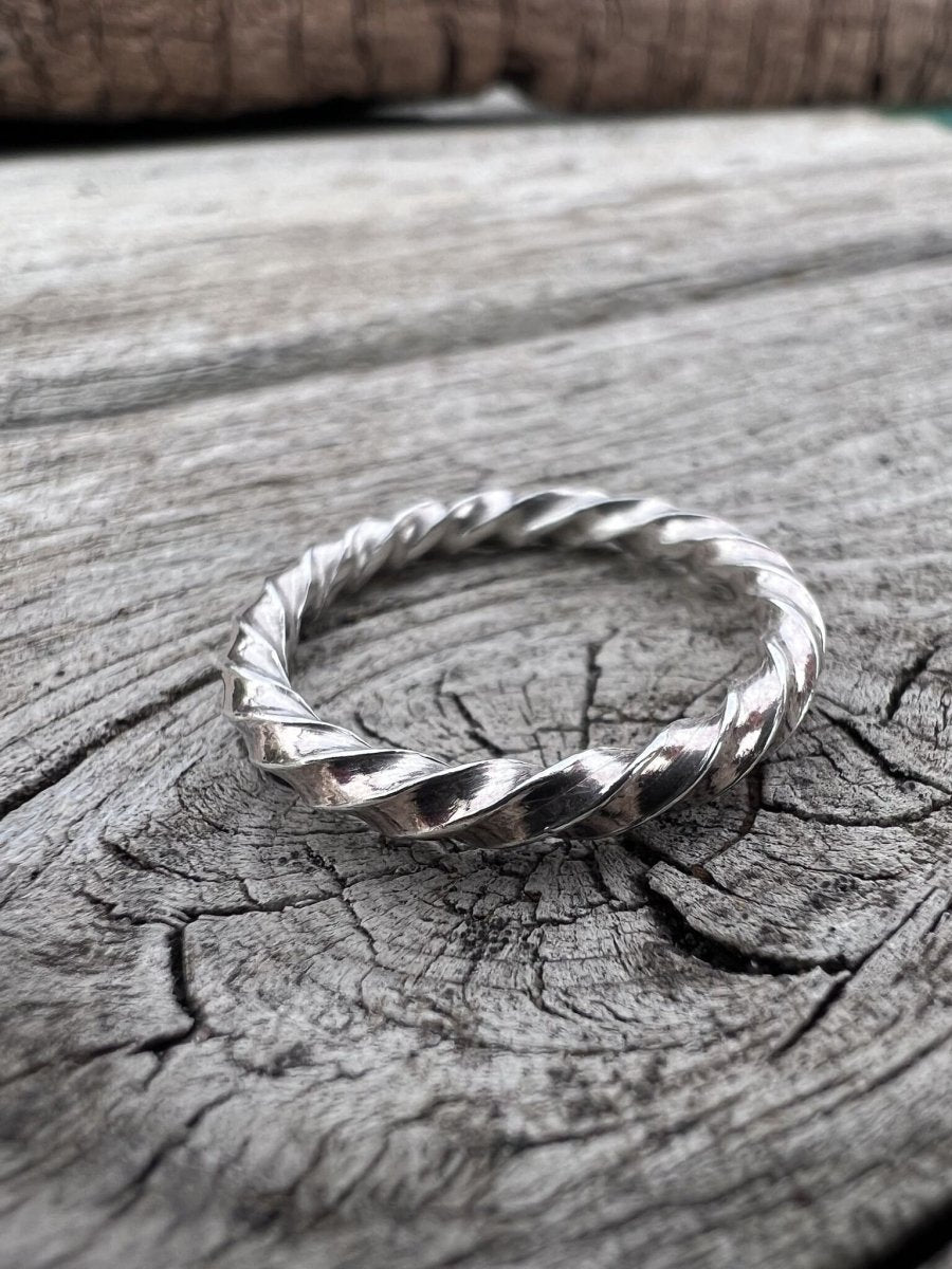 Thin sterling silver square twist ring on weathered wood