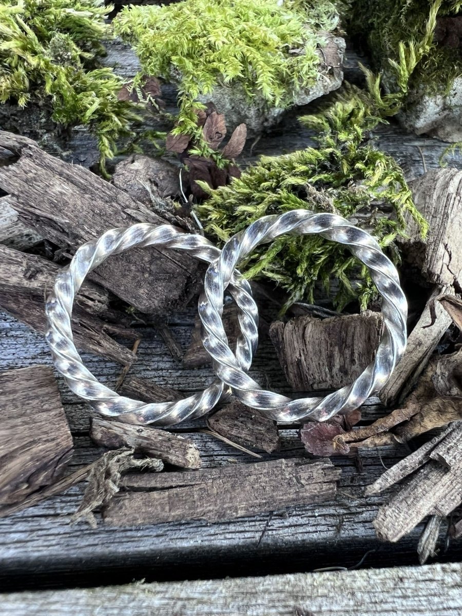Two recycled silver square twist rings styled together on weathered wood with green moss