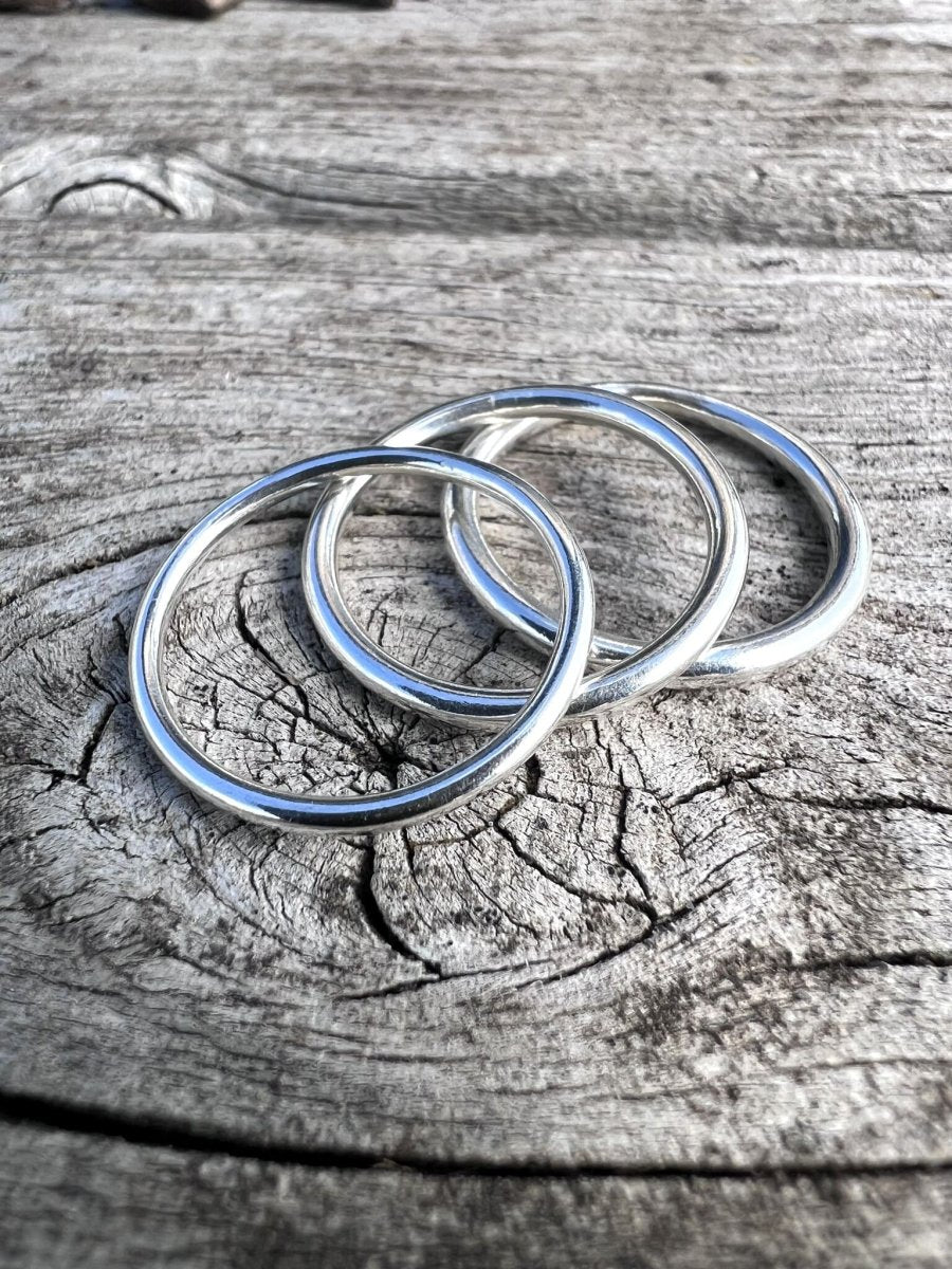 Set of slim recycled sterling silver thin stacking rings on weathered wood, minimalist jewellery