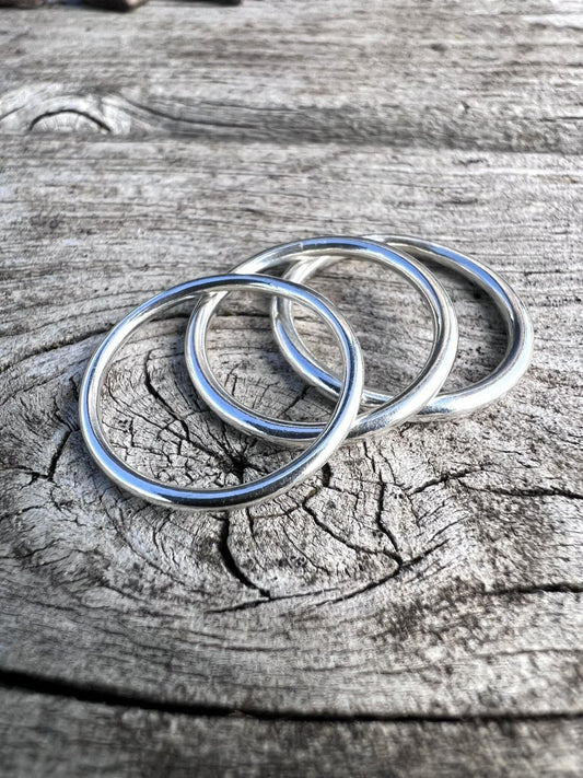 Set of slim recycled sterling silver thin stacking rings on weathered wood, minimalist jewellery