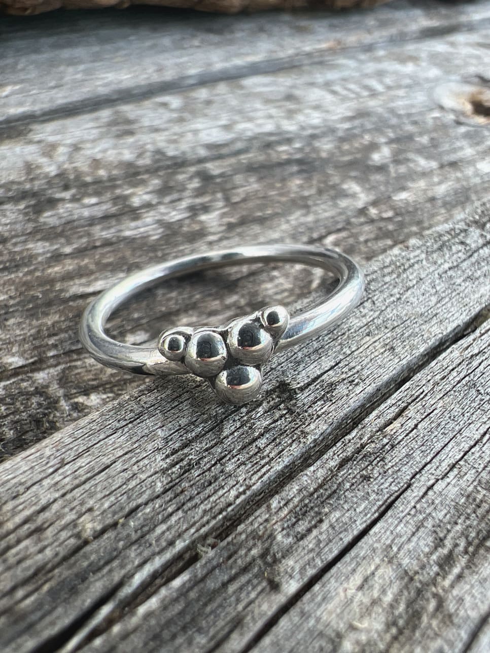 Handmade sterling silver triple granule ring on driftwood, front view angle