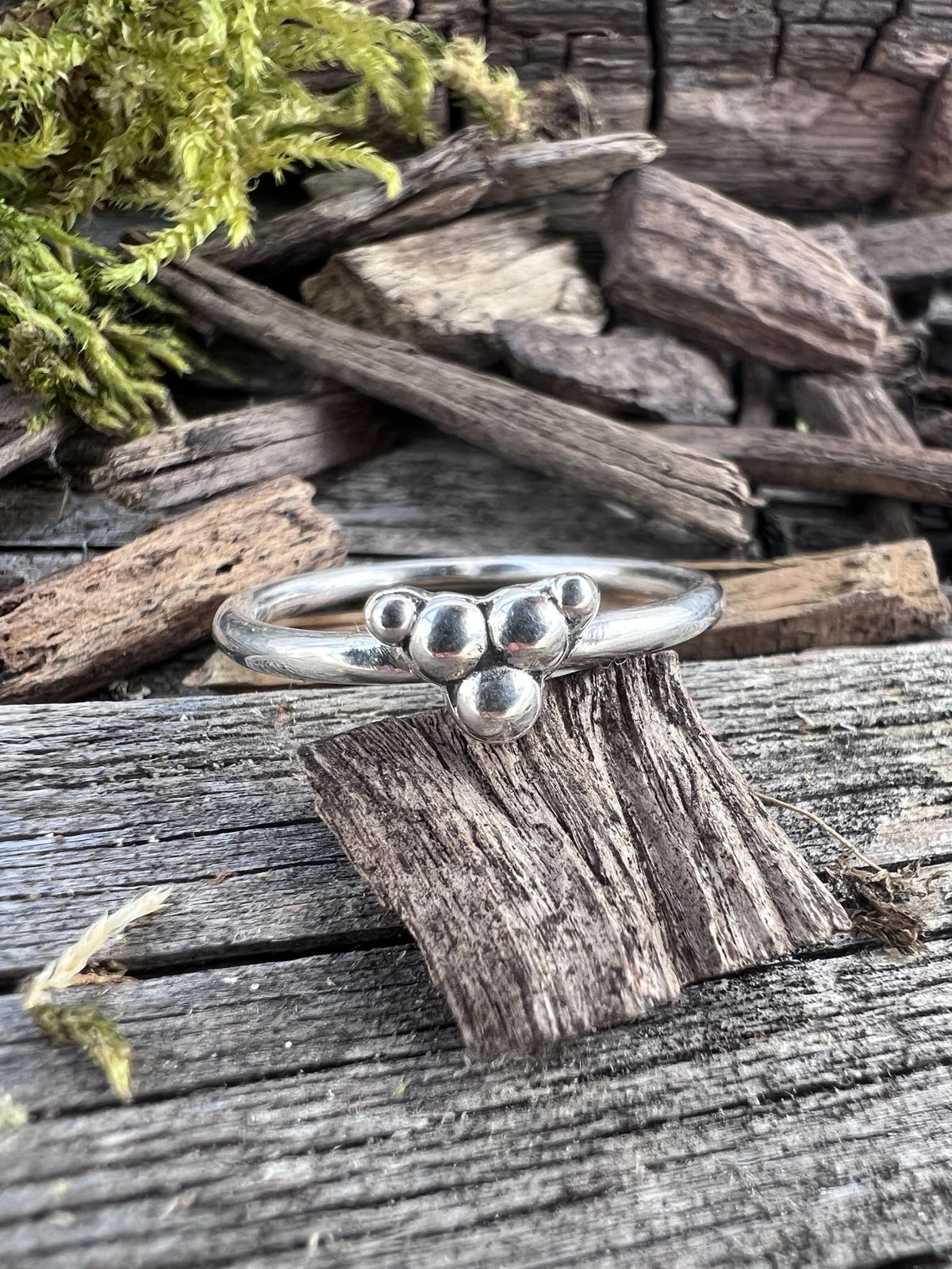 Recycled sterling silver triple granule ring on driftwood, showing the fine band with three silver granule details