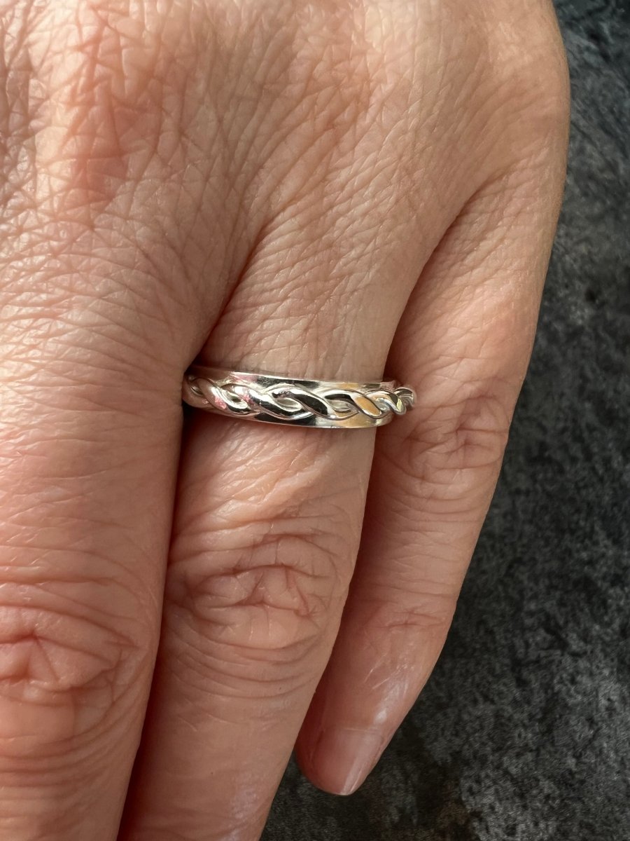 Sterling silver twisted plait ring worn on a finger, showing the braided band detail and comfortable fit