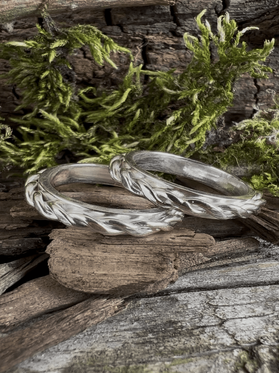 Twisted plait recycled silver rings resting against mossy stone, styled in a natural setting