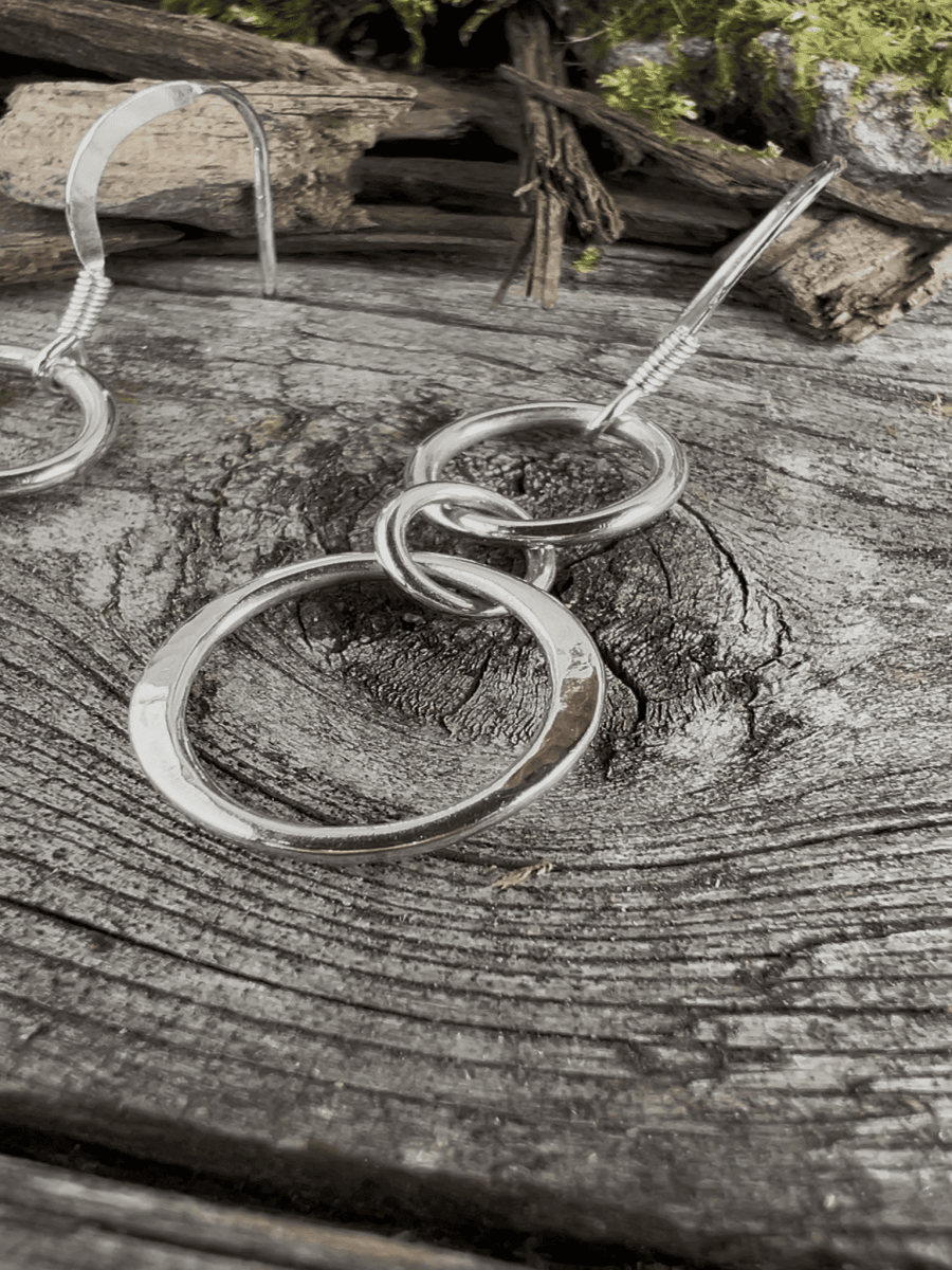 Recycled silver unity drop earrings on weathered wood, styled to show the double circle design from the front