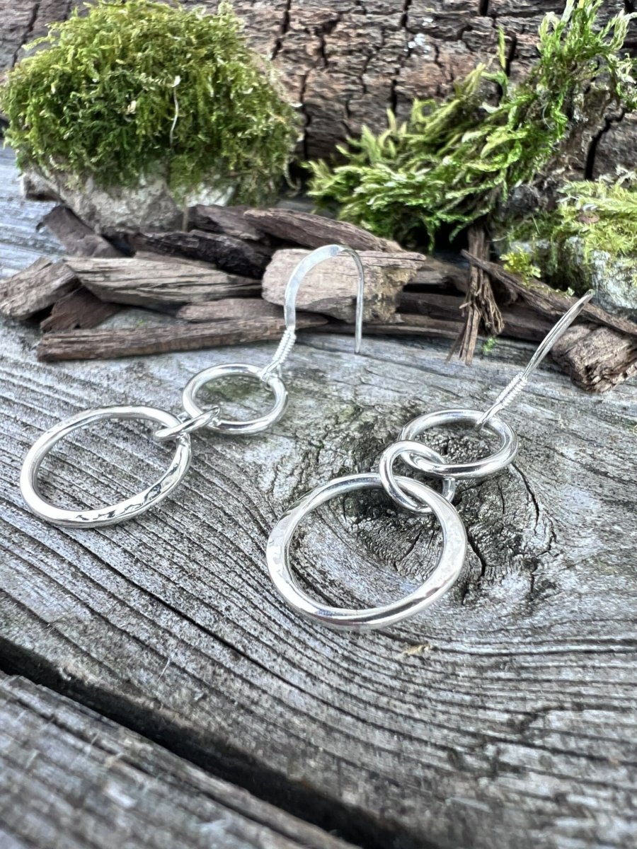 Recycled sterling silver unity drop earrings on weathered wood, showing the linked double circle design