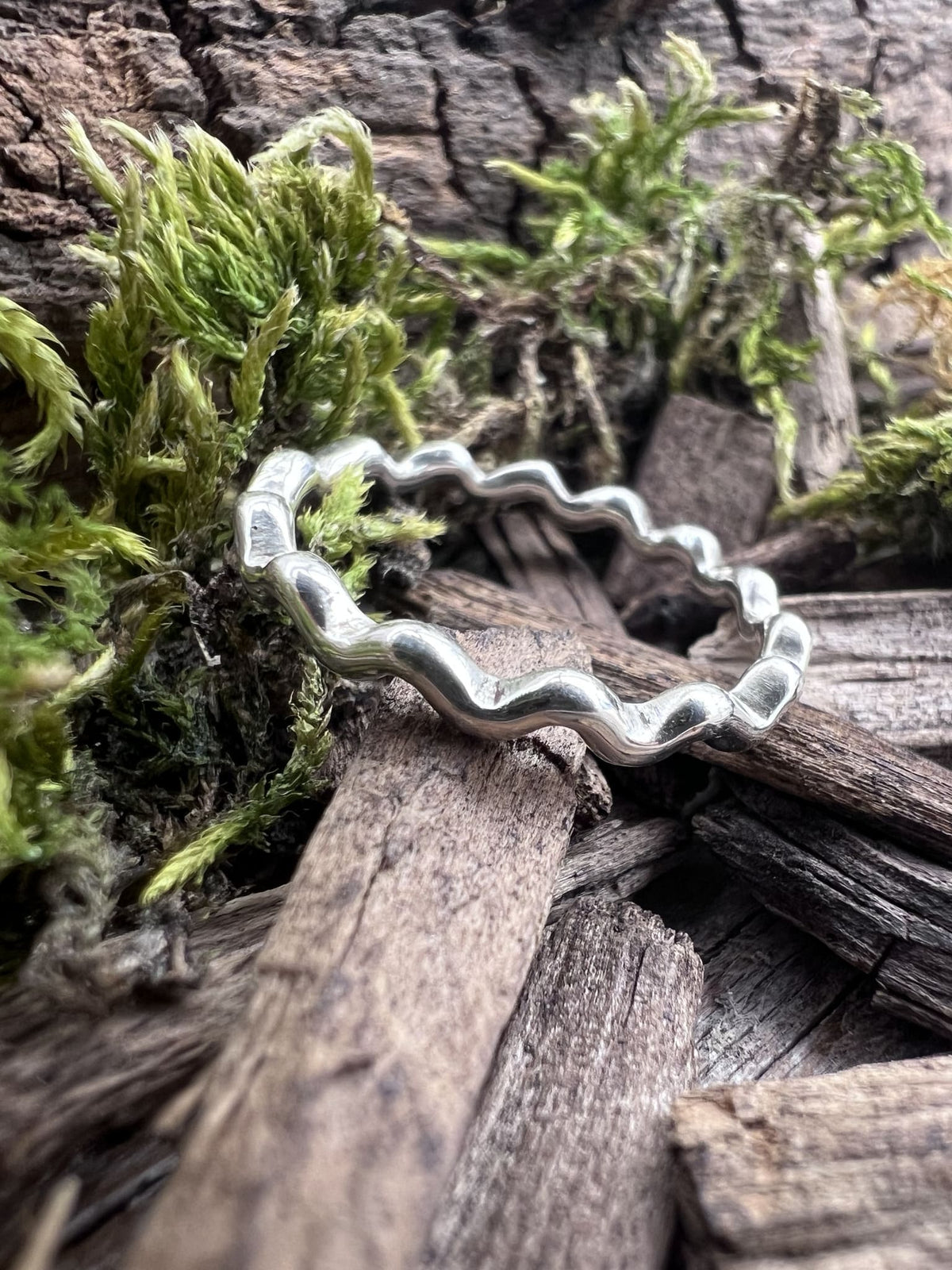 Recycled sterling silver wave ring on mossy driftwood, handmade Isle of Wight jewellery