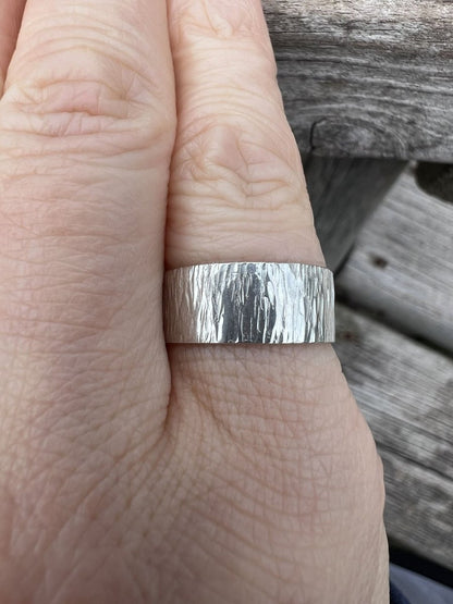 Sterling silver wide band ring with bark texture worn on a finger, showing the bold band width and natural surface finish