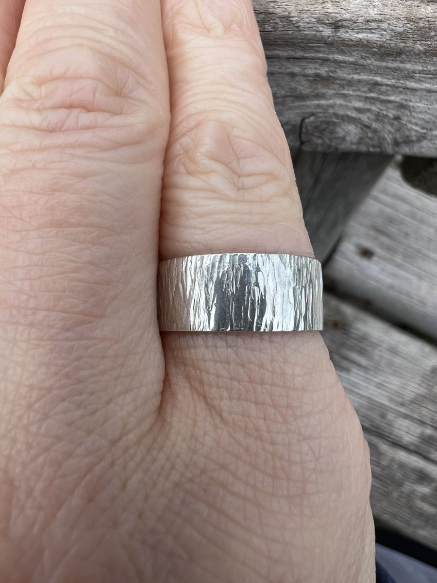 Sterling silver wide band ring with bark texture worn on a finger, showing the bold band width and natural surface finish
